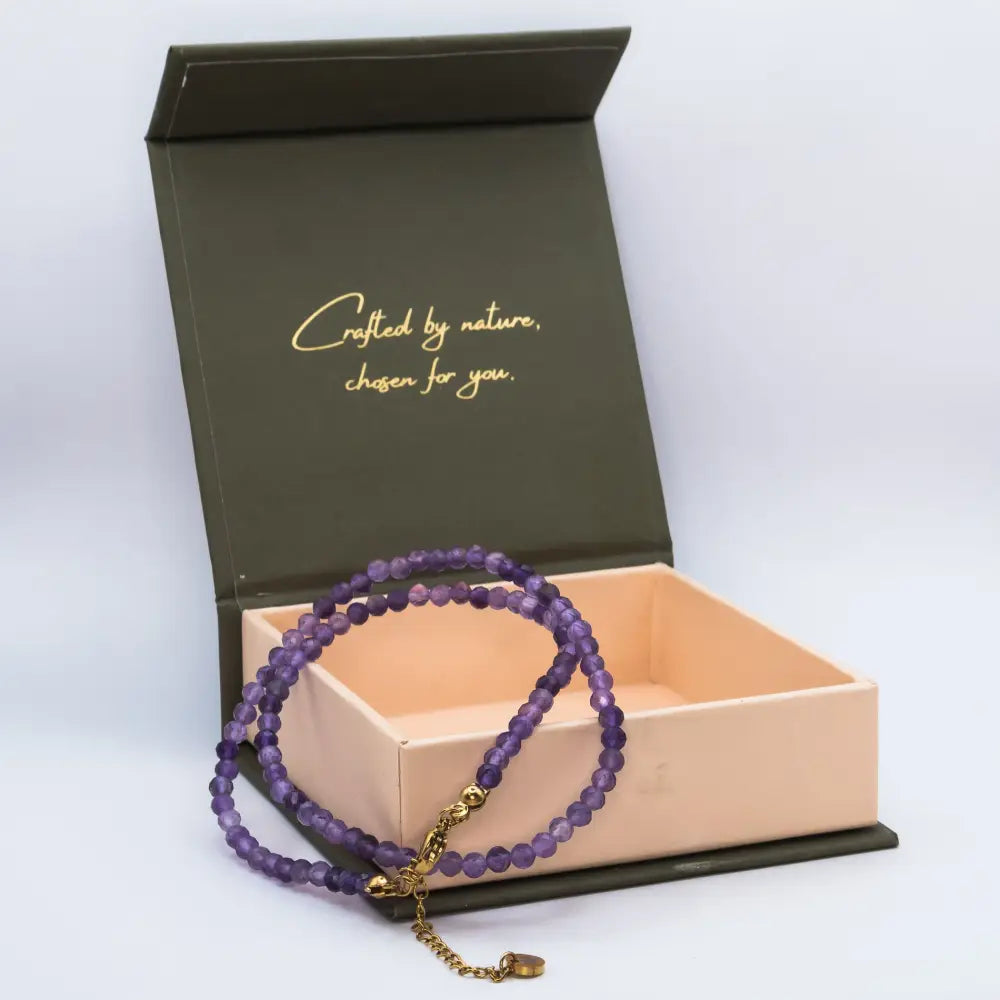Amethyst Faceted Round Necklace with gold charm on a cream and olive green branded box and light grey background