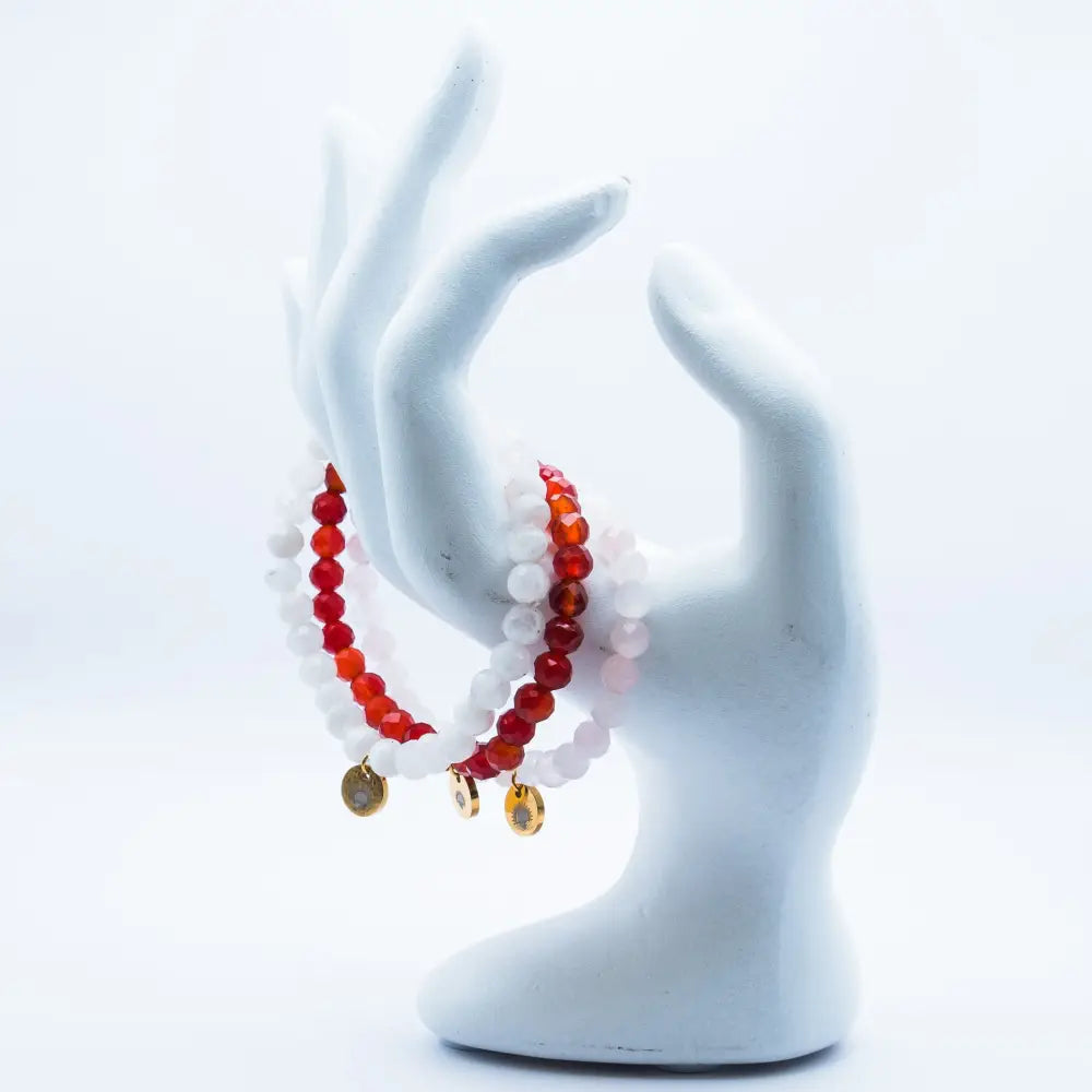 Rose Quartz, Moonstone, and Carnelian beaded bracelets with gold charms on a white mannequin hand.