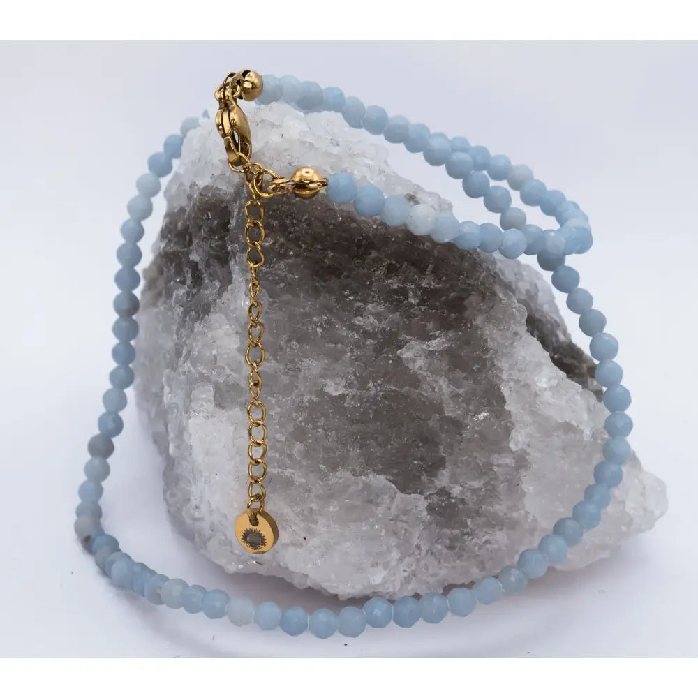 Angelite Faceted Necklace with gold charmon a white and grey stone with light background