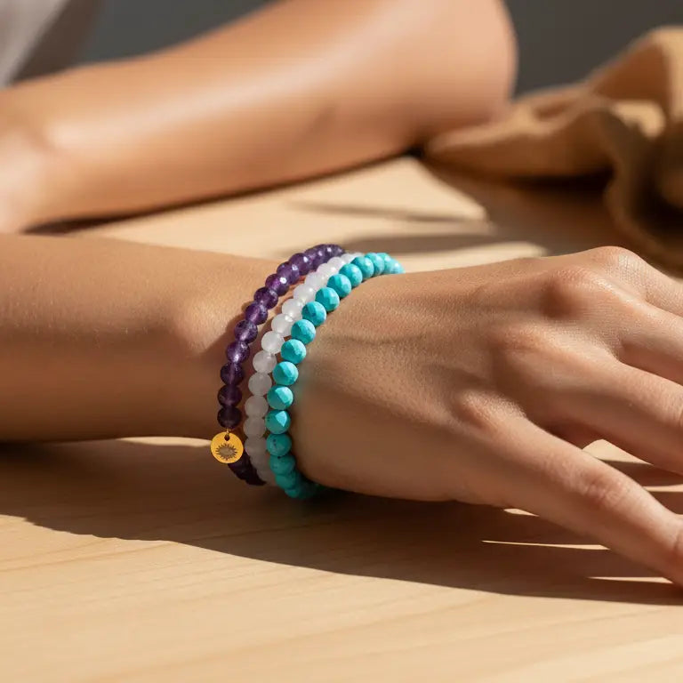 Rose Quartz, Amethyst, and Turquoise faceted beaded bracelets with gold charm on a wrist and blurred background