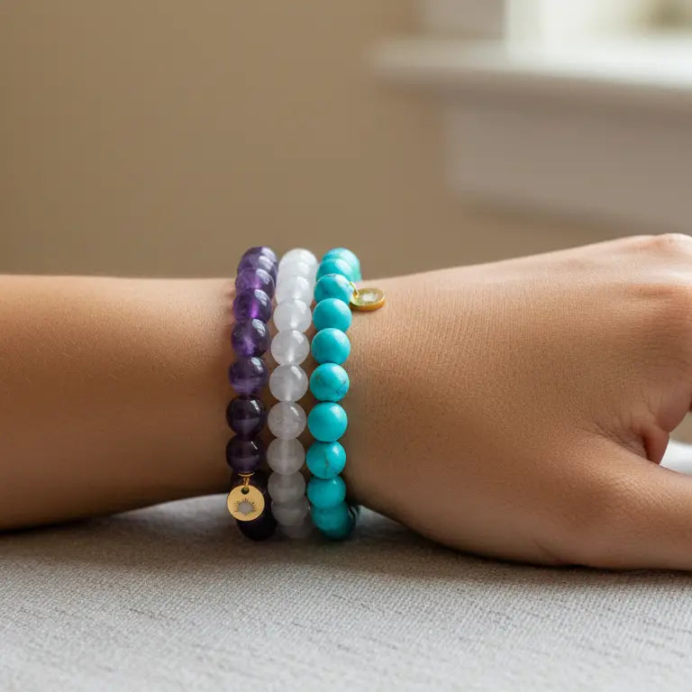 Rose Quartz, Amethyst, and Turquoise beaded bracelets with gold charms on a wrist and blurred background