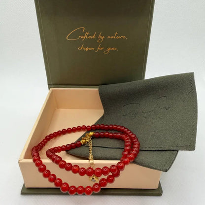 Carnelian Beaded Necklace with gold charm on an olive green pouch in a cream and olive green branded box