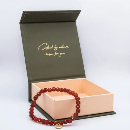 Carnelian Faceted Bracelet with gold charm on a cream and olive green branded box and a light grey background