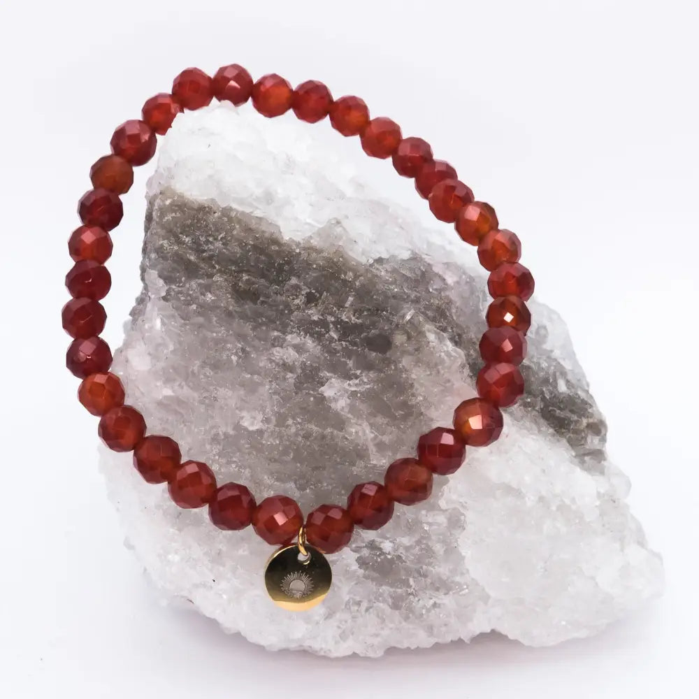 Carnelian Faceted Bracelet with gold charm on a white and grey stone and light background