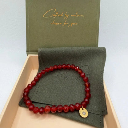 Carnelian Faceted Bracelet with gold charm on an olive green pouch in a cream and olive green branded box 