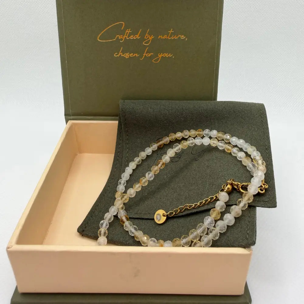 Citrine Faceted Necklace with gold charm on an olive green pouch in a cream and olive green branded box