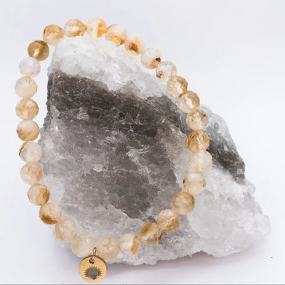 Citrine Faceted Bracelet with gold charm on a white and grey stone and neutral background
