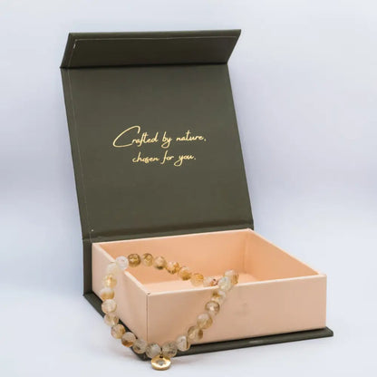 Citrine Faceted Bracelet with gold charm on a cream and olive green branded box and light grey background