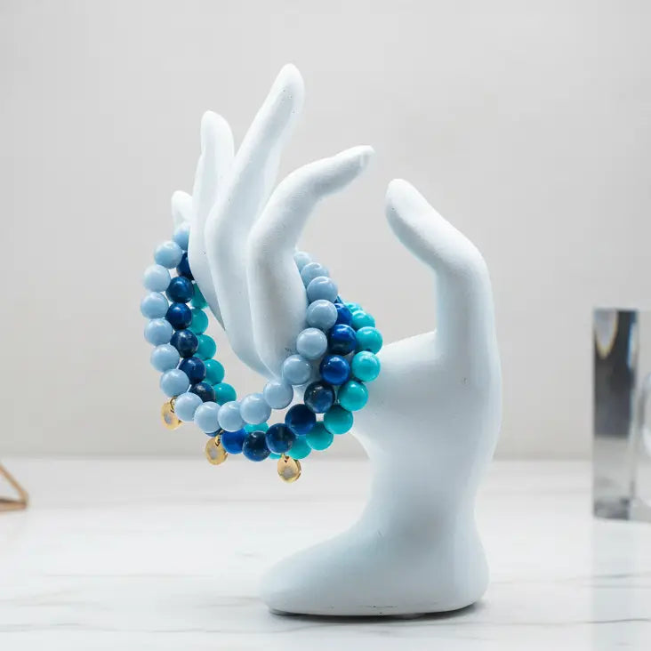 Lapis Lazuli, Turquoise, and Angelite beaded bracelet with gold charms on a mannequin hand and light background