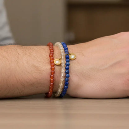 Citrine, Carnelian, and Lapis Lazuli beaded bracelets with gold charms on a wrist with netural blurred background