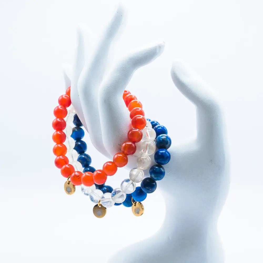 Citrine, Carnelian, and Lapis Lazuli beaded bracelets with gold charms on a mannequin hand and white backgrund