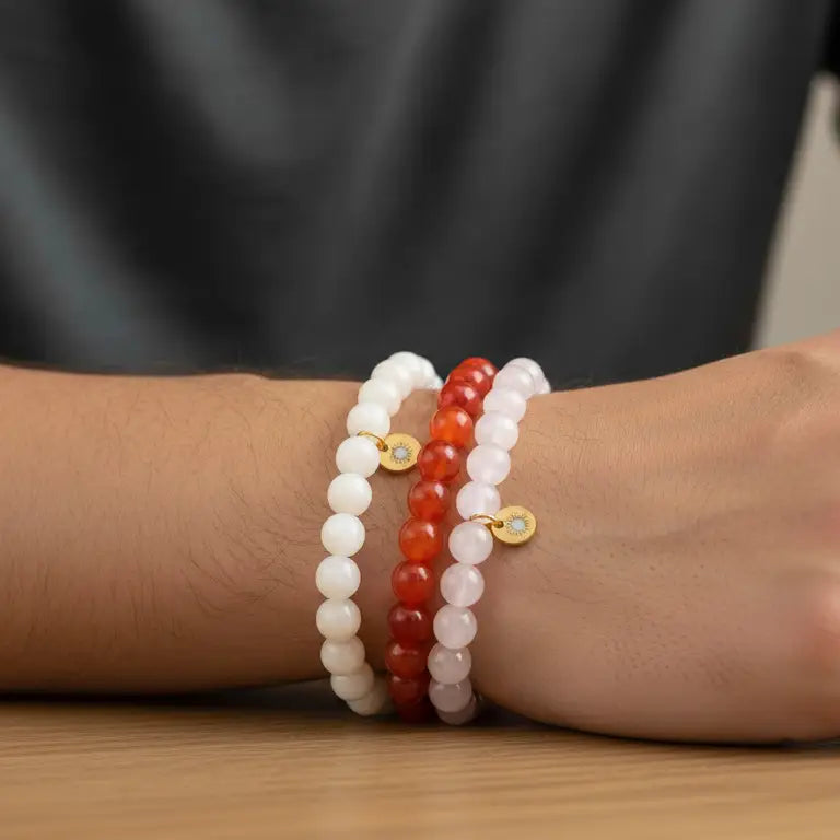 Moonstone, Carnelian, and Rose Quartz beaded bracelets with gold charms on a wooden surface and neutral background