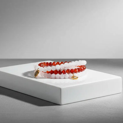 Set of Rose Quartz, Moonstone, and Carnelian beaded bracelets with gold charms on a white platform with a gray background