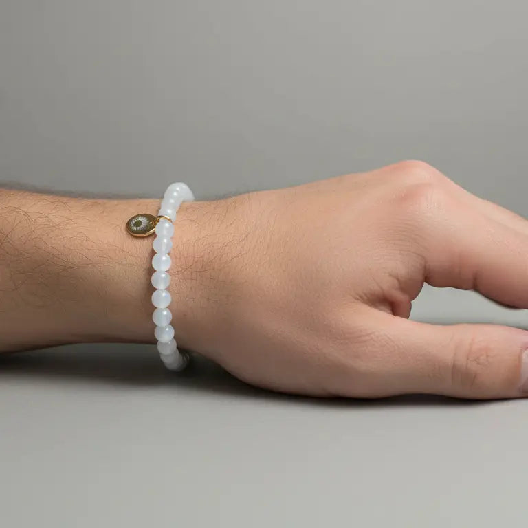 Moonstone Beaded Bracelet with gold charm on a wrist on a grey background