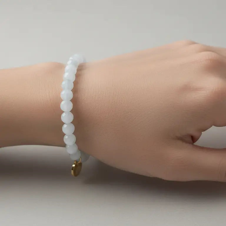 Moonstone Faceted Bracelet with gold charm on a wrist and cream background
