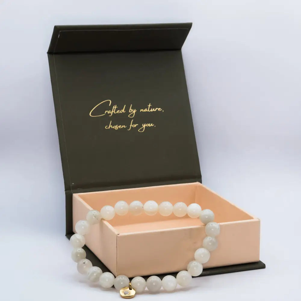 Moonstone Beaded Bracelet with gold charm on a cream and olive green branded box and light grey background