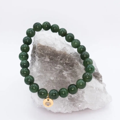 Nephrite Jade Beaded Bracelet with gold charm on a white and grey stone and neutral background