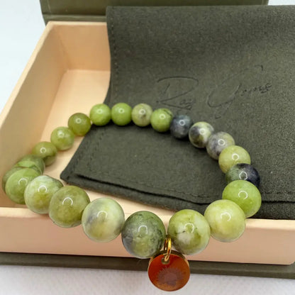 Peridot Beaded Bracelet with gold charm on an olive green pouch in a cream and olive green box