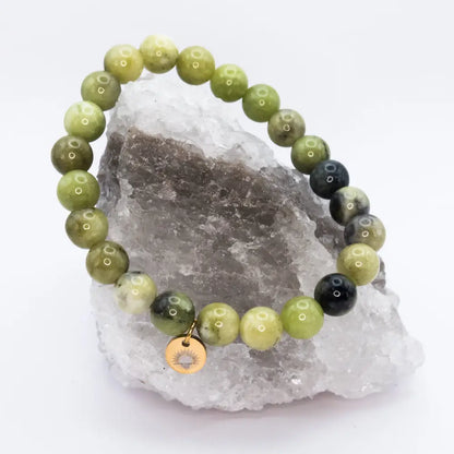 Peridot Beaded Bracelet with gold charm on a white and grey stone and neutral background