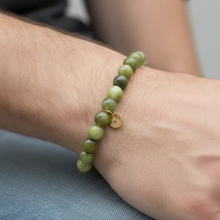 Peridot Beaded Bracelet with gold charm on a wrist against a denim fabric and blurred background