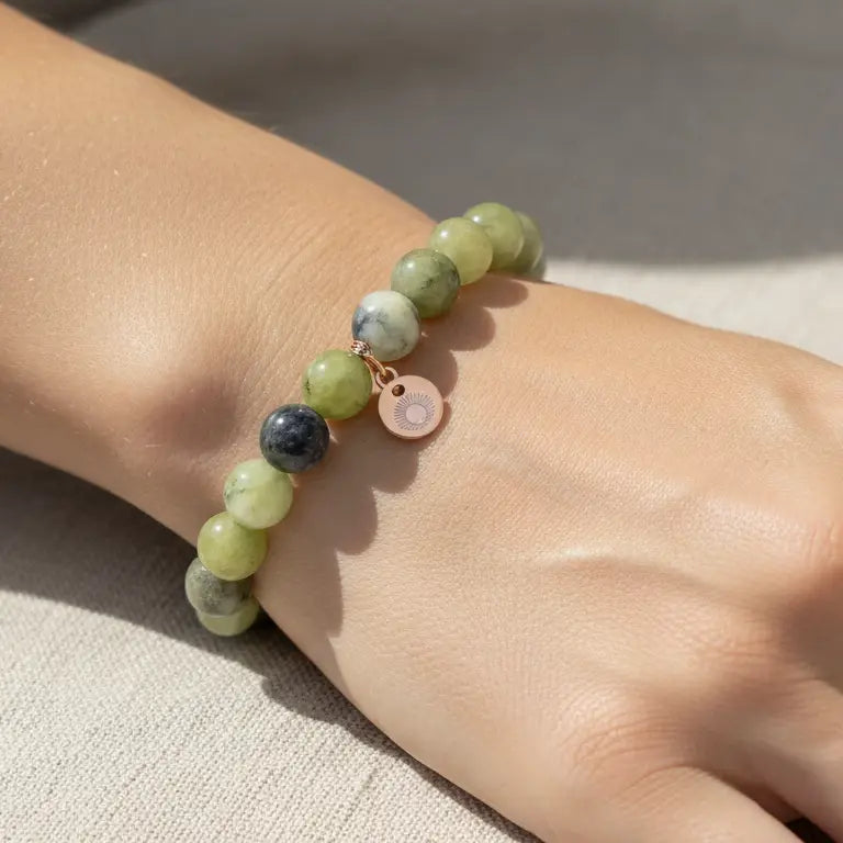 Peridot Beaded Bracelet with gold charm on a  wrist against a light fabric 