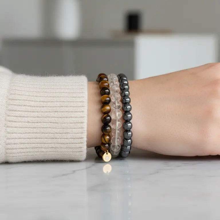 Person wearing Tiger Eye, Hematite, and Citrine faceted beaded bracelets with gold charm on a neutral background