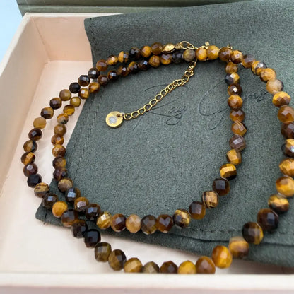 Tiger Eye Faceted Necklace with gold charm on an olive green pouch in a cream and olive green box