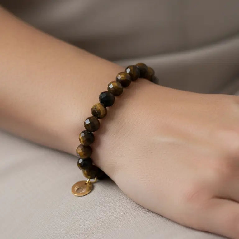 Tiger Eye Faceted Bracelet with gold charm on a wrist and grey background