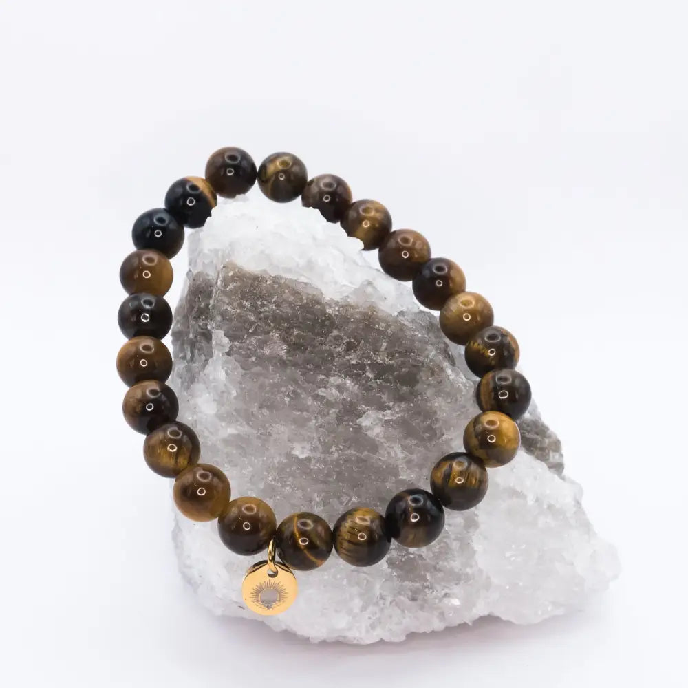 Tiger Eye Beaded Bracelet with gold charm on a white and grey stone and neutral background